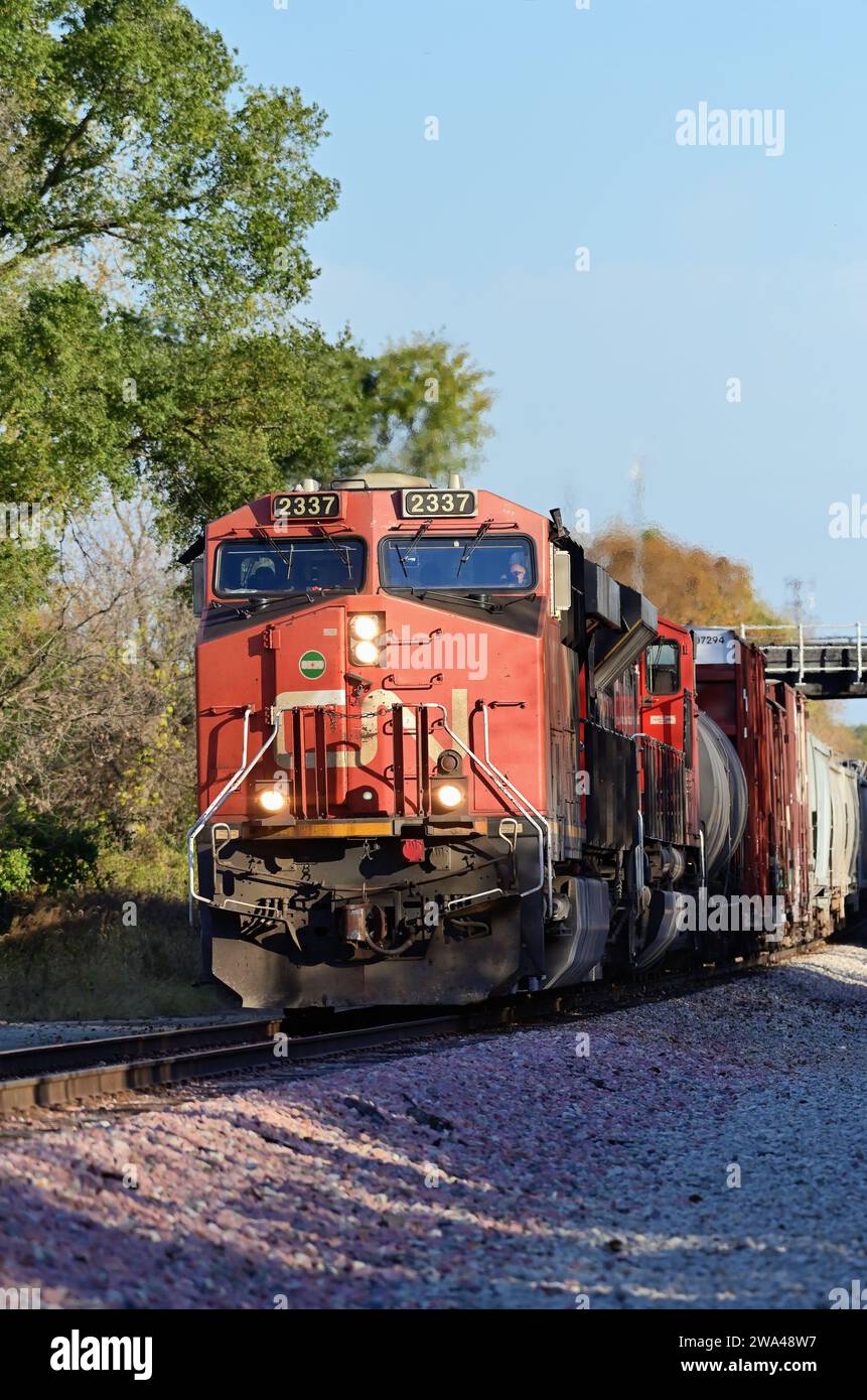 Wayne, Illinois, USA. Ein Güterzug der Canadian National Railway, der unter einer Brücke vorbeifährt und eine weitere Bahnstrecke befährt. Stockfoto
