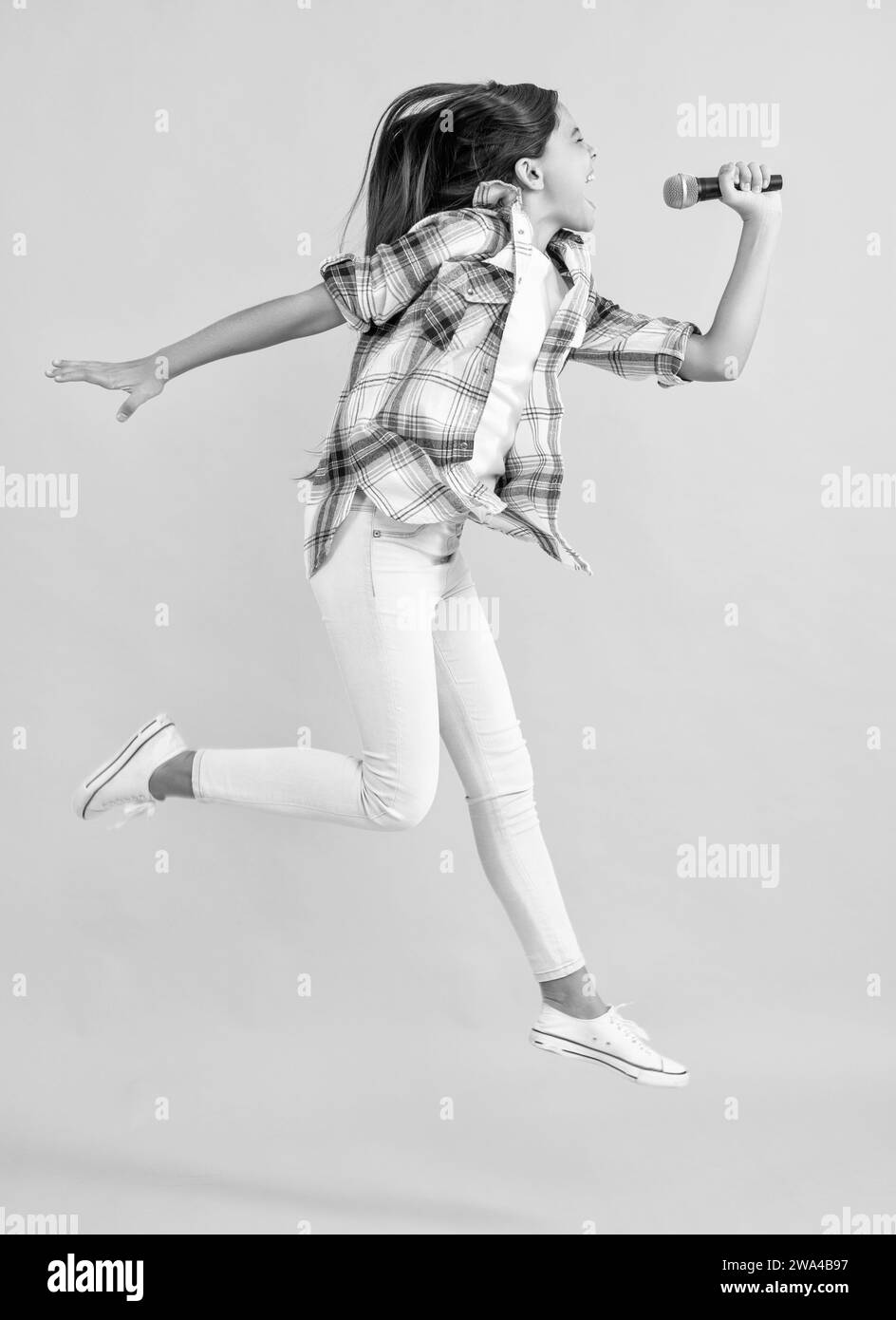 Karaoke-Sängerin für Teenager, die ins Studio springt. Teenager-Karaoke-Sängerin im Hintergrund. Stockfoto