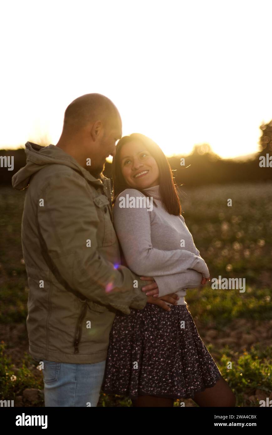 Der Mann umarmt seine Freundin bei Sonnenuntergang, umgeben von einer natürlichen Umgebung. Stockfoto