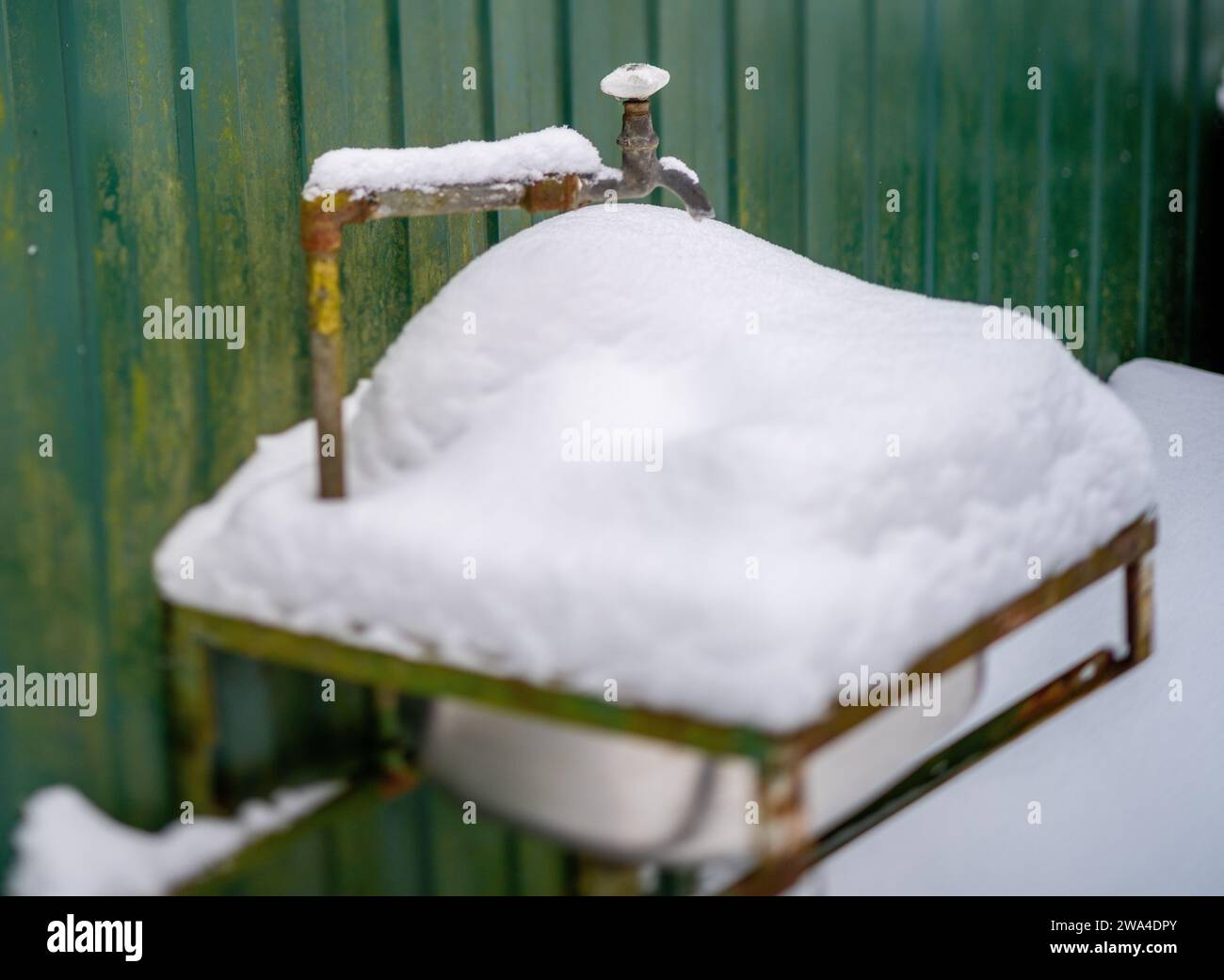 Waschbecken im Freien voller Schnee und gefrorenem Wasserhahn, keine Leute Stockfoto