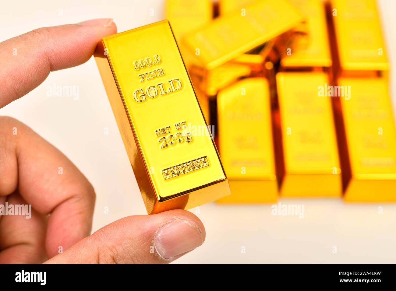 Nahaufnahme Hand hält Goldbarren im Hintergrund gibt es einen Haufen Goldbarren, Goldinvestitionskonzept Stockfoto