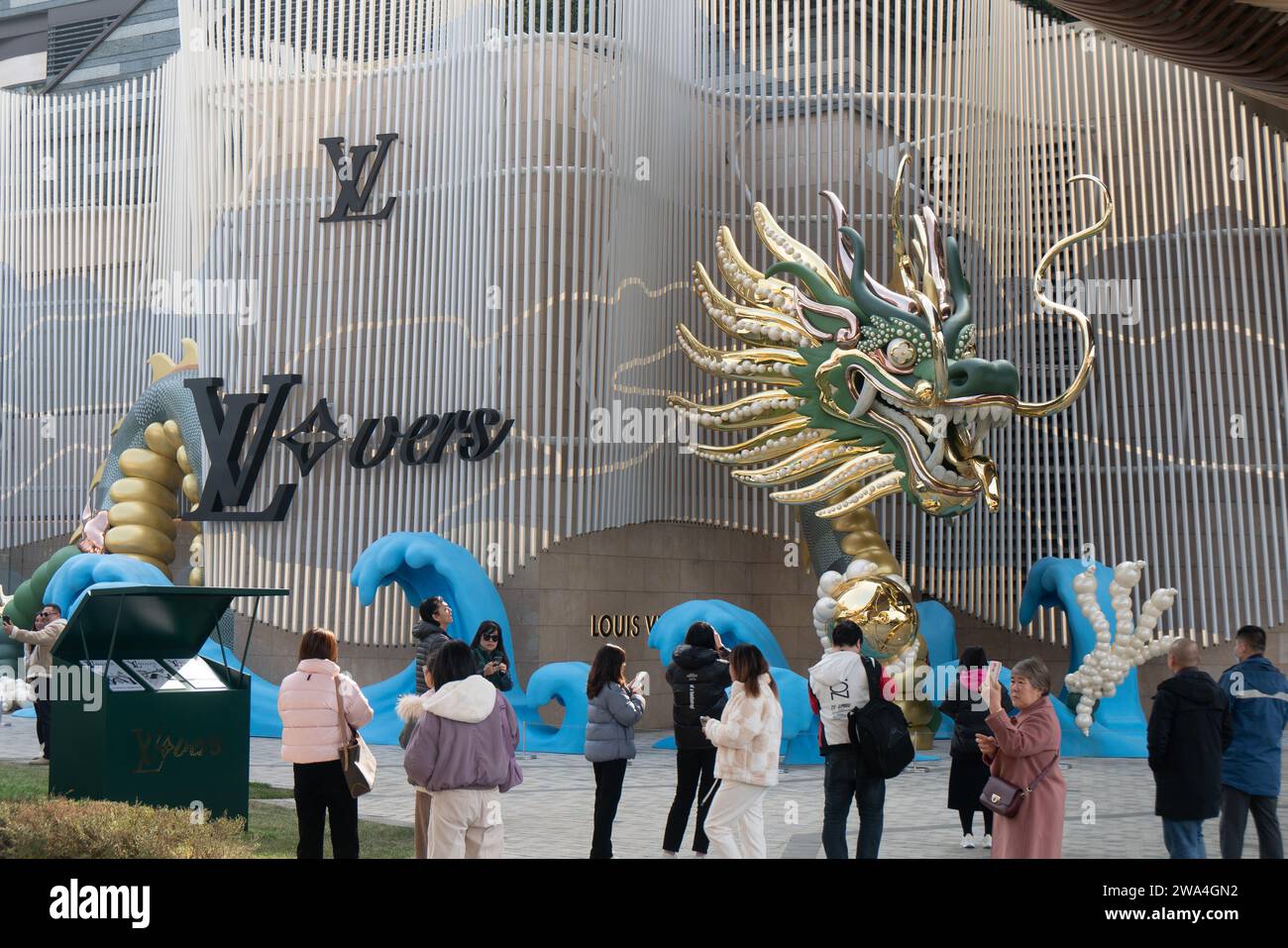 SHANGHAI, CHINA - 2. JANUAR 2024 - Besucher sehen eine Drachenskulptur aus Gold, Grün und Jade, die von der Luxusmarke Louis Vuitton in Shanghai, China, geschaffen wurde. Stockfoto