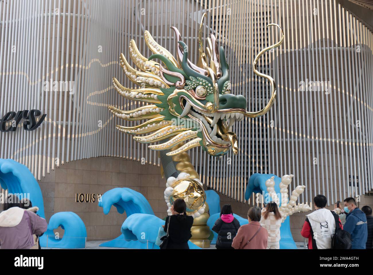 SHANGHAI, CHINA - 2. JANUAR 2024 - Besucher sehen eine Drachenskulptur aus Gold, Grün und Jade, die von der Luxusmarke Louis Vuitton in Shanghai, China, geschaffen wurde. Stockfoto