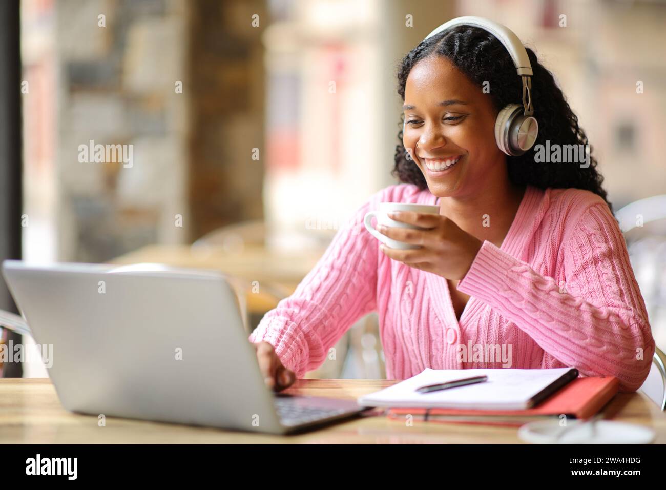 Glückliches E-Learning für schwarze Schüler mit Laptop und Kopfhörer, die Kaffee in einer Bar trinken Stockfoto