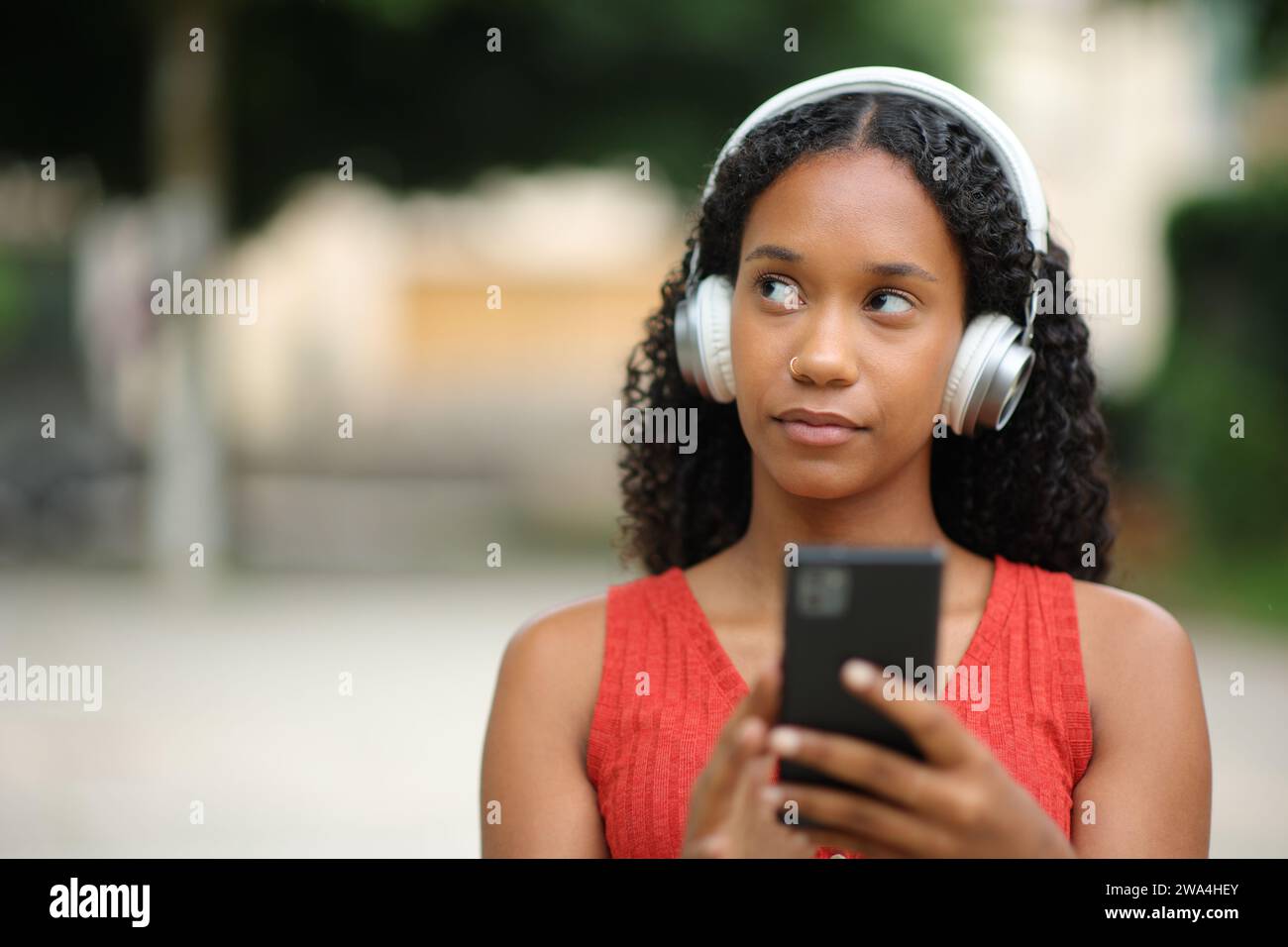 Vorderansicht Porträt einer ernsten nachdenklichen schwarzen Frau, die Audio auf der Straße hört Stockfoto