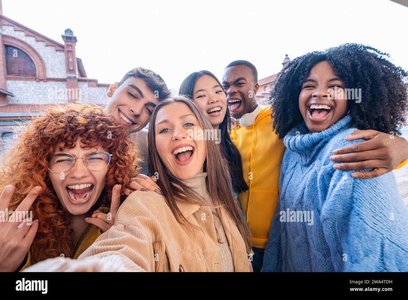 Fröhliche Gruppe von Freunden posiert für ein verspieltes Selfie, das vor Lachen und lebhaften Ausdrücken strotzt Stockfoto