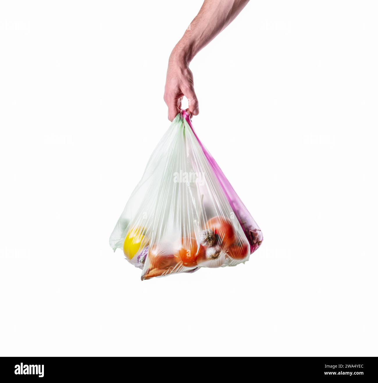 Ein Mann hält Plastiktüten in der Hand mit Gemüse auf weißem Hintergrund. Umweltverschmutzung durch Kunststoff. Isoliert auf weißem Hintergrund. Stockfoto