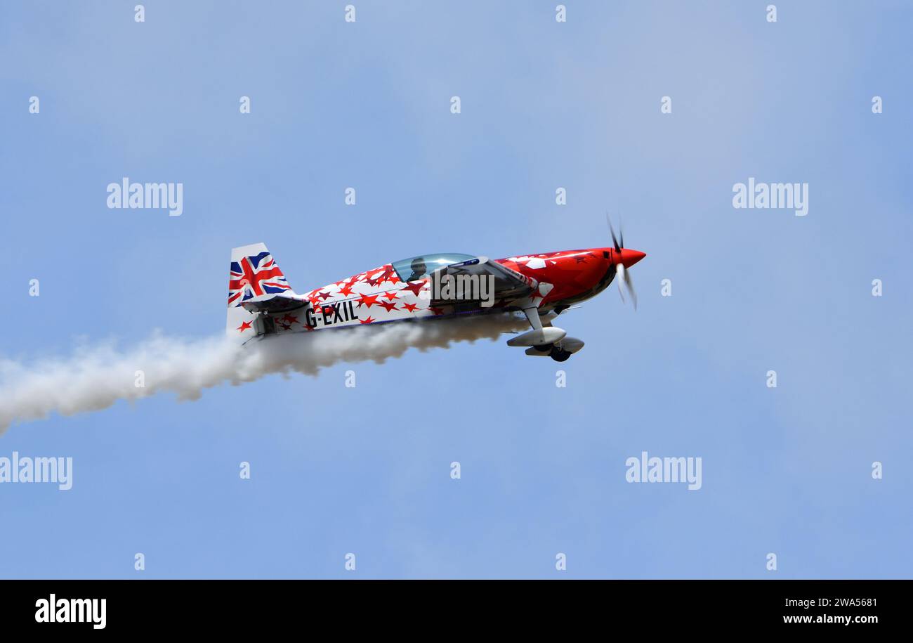 Global All Stars Extra 300S Stuntflugzeug im Flug mit Rauch Stockfoto