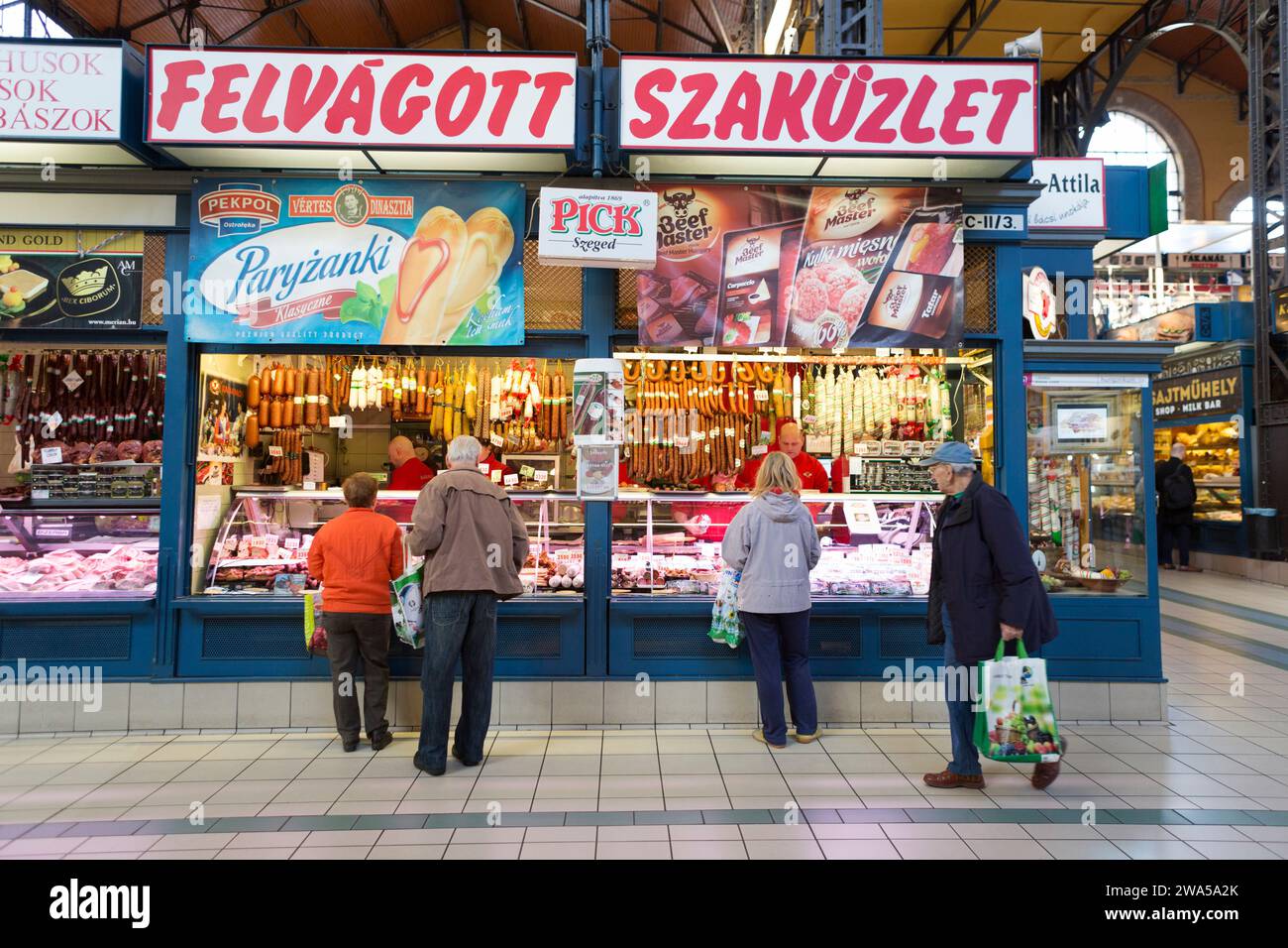 Ungarn, Budapest, Einheimische an einem traditionellen Fleischstand auf dem zentralen überdachten Stadtmarkt. Stockfoto