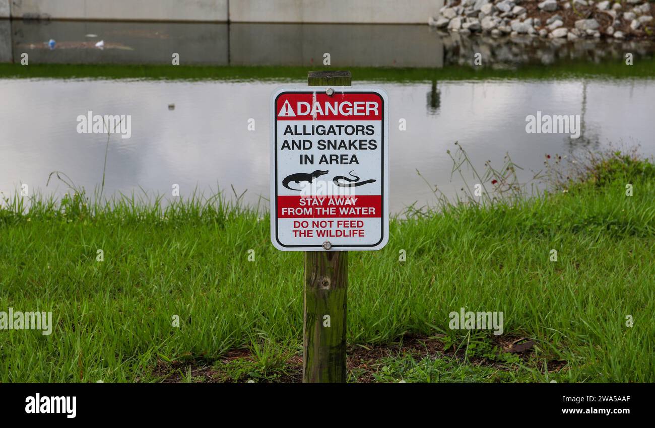 Ein Schild, das vor Alligatoren und Schlangen in der Nähe eines Baches in Florida USA warnt. Stockfoto