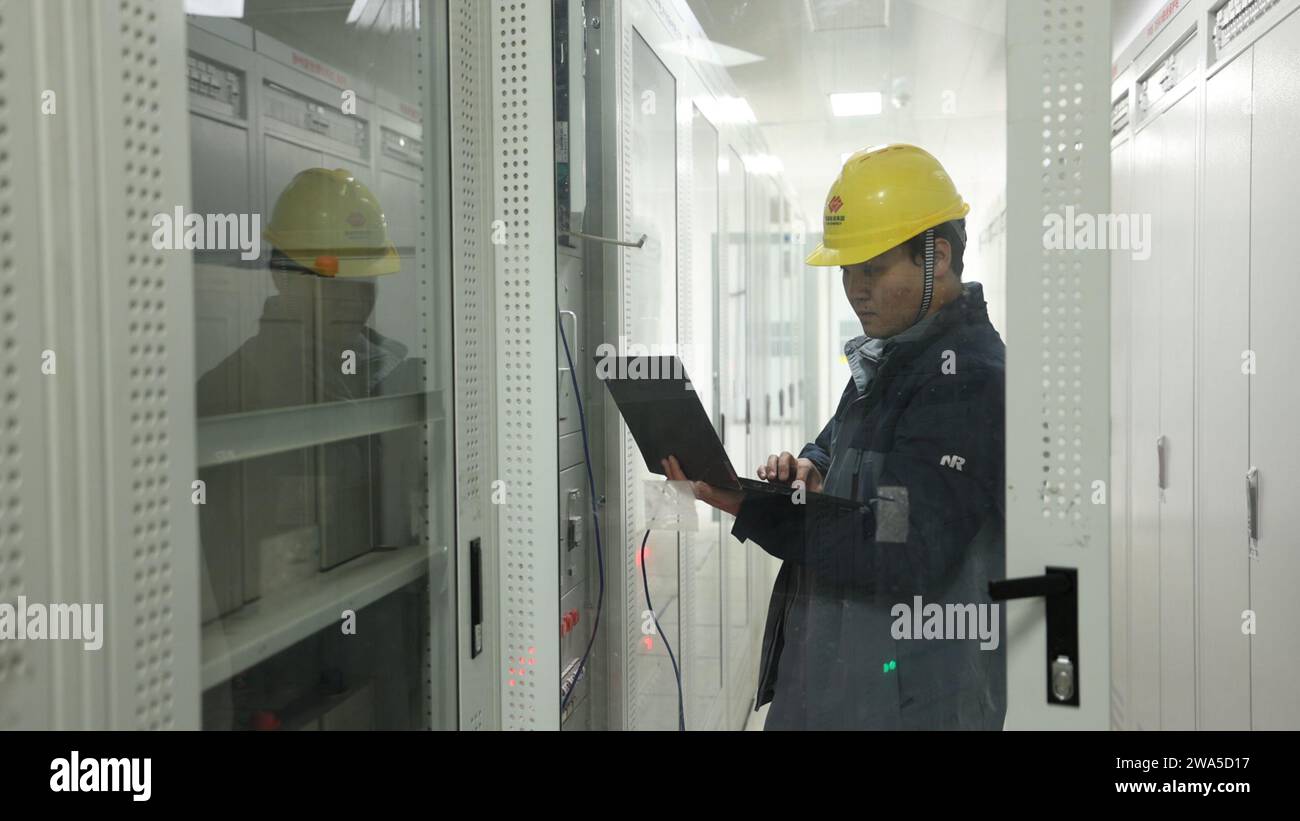 Lhasa, Chinas autonome Region Xizang. Dezember 2023. Ein Mitarbeiter testet Ausrüstung bei einem großen Windkraftprojekt in Nagqu, südwestchinesischer Autonomen Region Xizang, 14. Dezember 2023. UM MIT „dem größten Windpark der Welt in Betrieb zu SEIN, der in Xizang in Betrieb ist“ Credit: Wang Yuhan/Xinhua/Alamy Live News Stockfoto