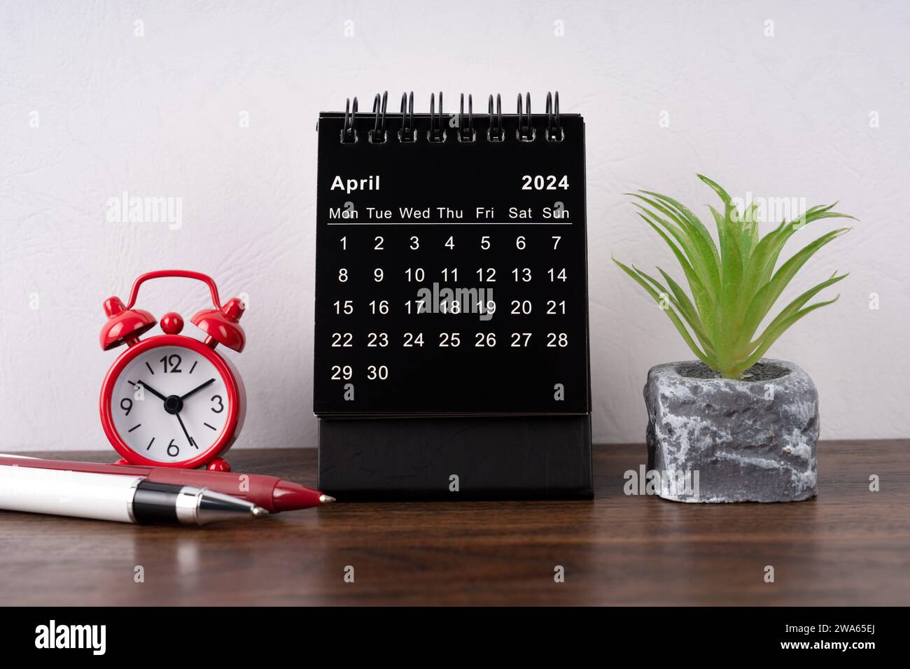 April 2024 Schreibtischkalender, Wecker und Topfpflanze Stockfoto