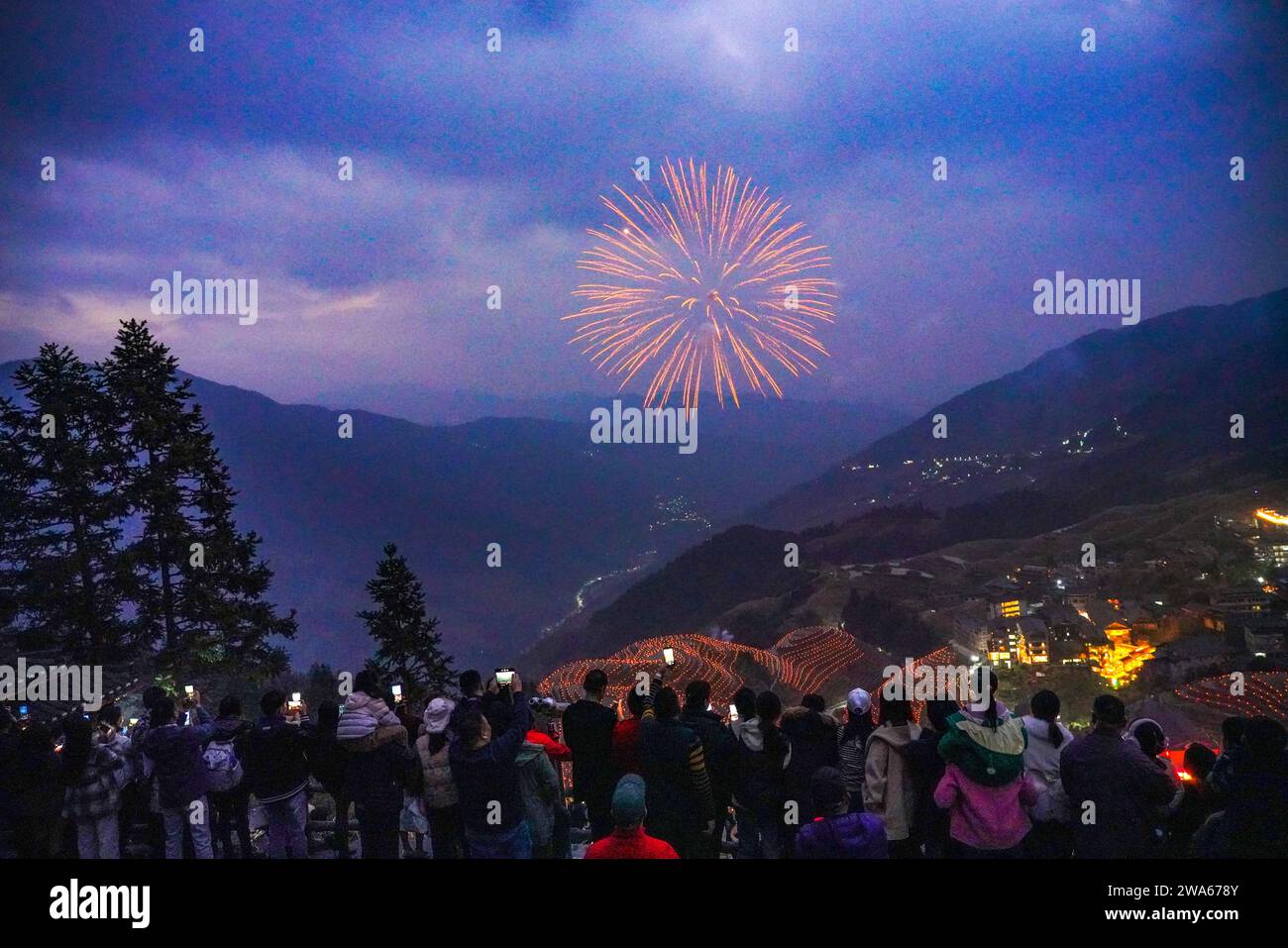 (240102) -- PEKING, 2. Januar 2024 (Xinhua) -- Touristen sehen ein Feuerwerk im Dorf Ping'an der Stadt Longji, County Longsheng, südchinesischer Autonomen Region Guangxi Zhuang, 31. Dezember 2023. (Foto: Pan Zhixiang/Xinhua) Stockfoto