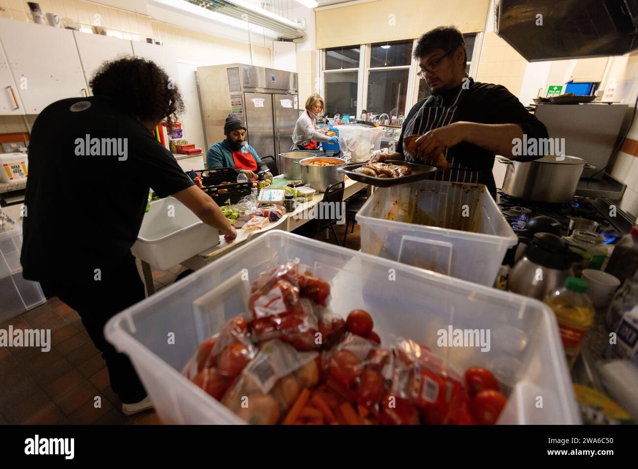 Ein Koch und Köche bereiten eine Mahlzeit in einer Gemeinschaftsküche im Granville Centre in Kilburn, London zu Stockfoto