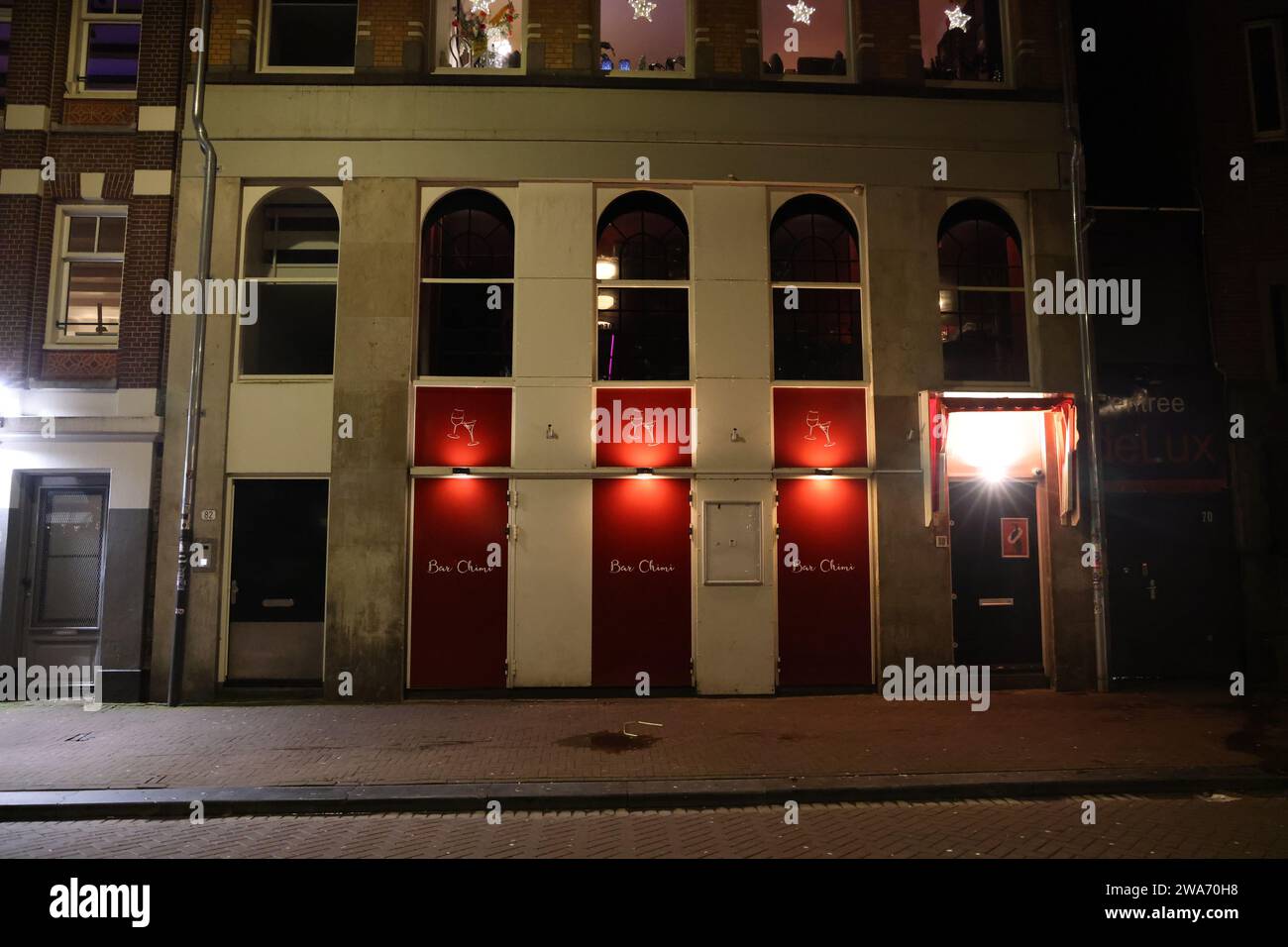 Nachtblick auf die Fassade des Restaurants Bar Chimi in Amsterdam, mit roten Türen Stockfoto