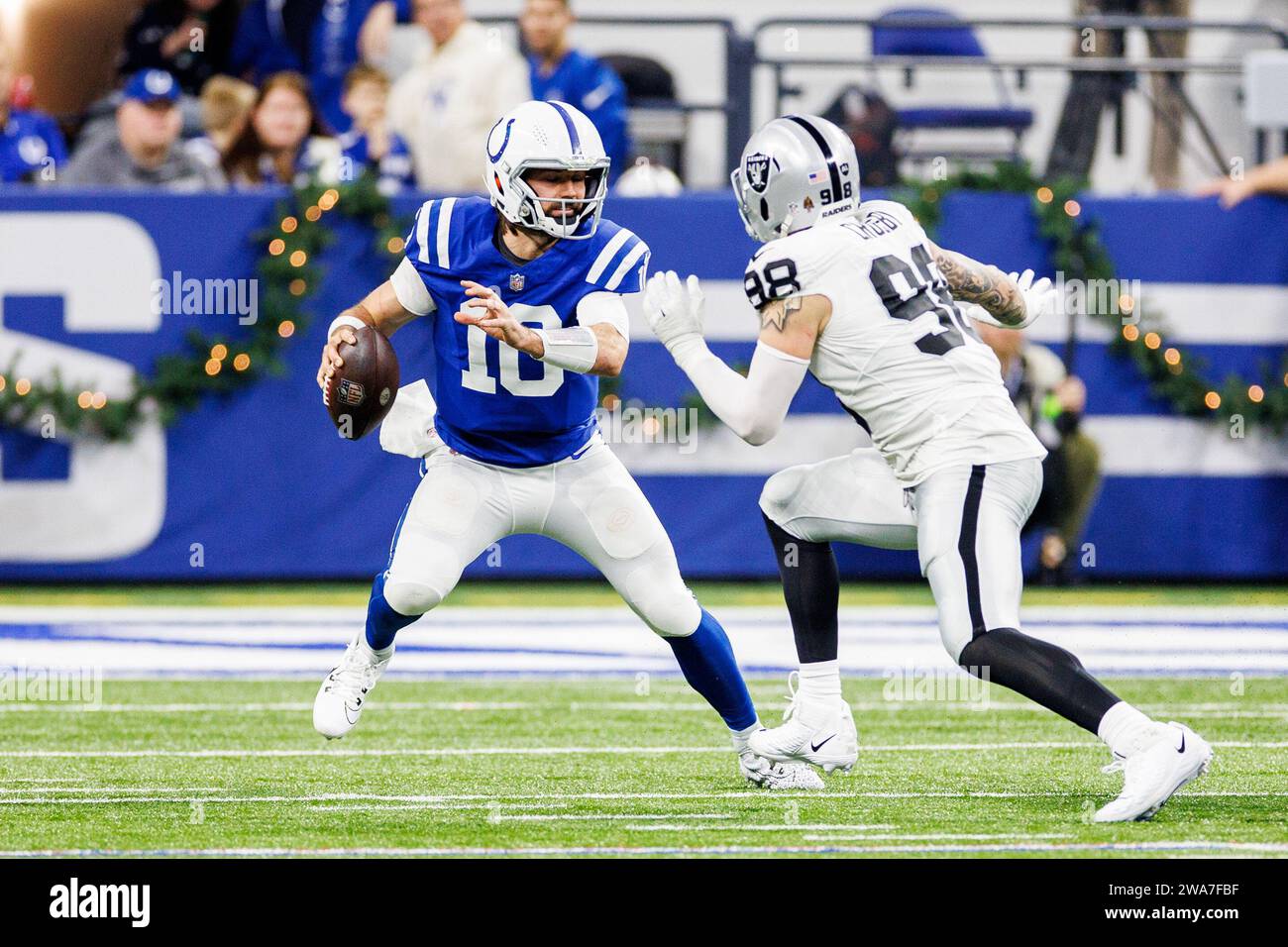 Indianapolis, Indiana, USA. Dezember 2023 31. Der Indianapolis Colts Quarterback Gardner Minshew (10) stürzt sich aus der Tasche, als der Defensivlineman Maxx Crosby (98) der Las Vegas Raiders im Lucas Oil Stadium in Indianapolis, Indiana, die Action des NFL-Fußballspiels verfolgt. John Mersits/CSM (Credit Image: © John Mersits/Cal Sport Media). Quelle: csm/Alamy Live News Stockfoto