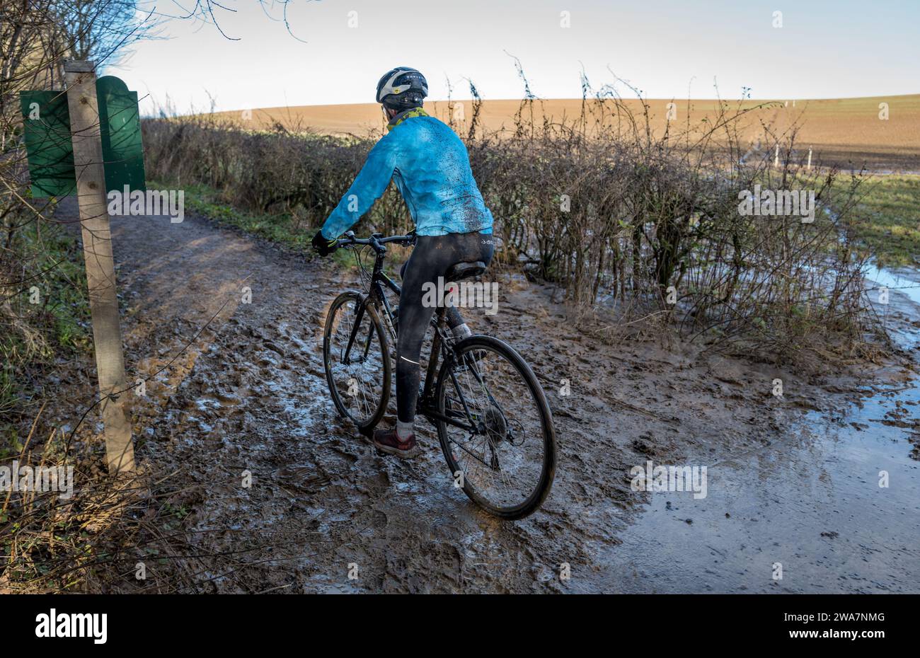 Weibliche Radfahrerin, die auf einer nassen und schlammigen Strecke fährt. Stockfoto