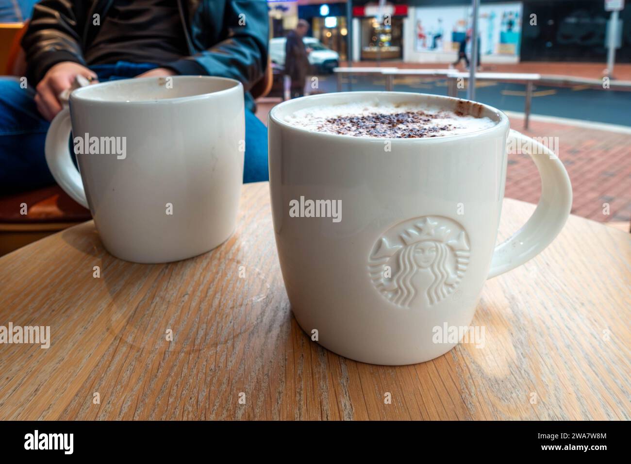 Ein Cappuccino in einem Starbucks-Café in einem Becher mit Markenzeichen auf einem Tisch. Stockfoto