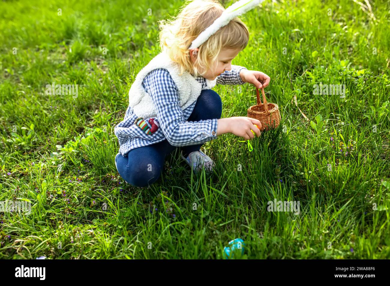 Kleines Mädchen sammelt bunte Ei im Park. Konzept der Osterjagd Stockfoto