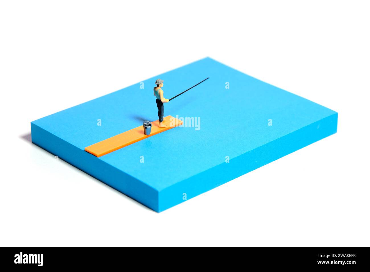 Kreative Miniaturmenschen spielzeugfiguren fotografieren. Installation von Haftnotizen. Ein Mann, der über einer Holzbrücke am Fluss, See oder Strand fischt. Isoliert auf W Stockfoto