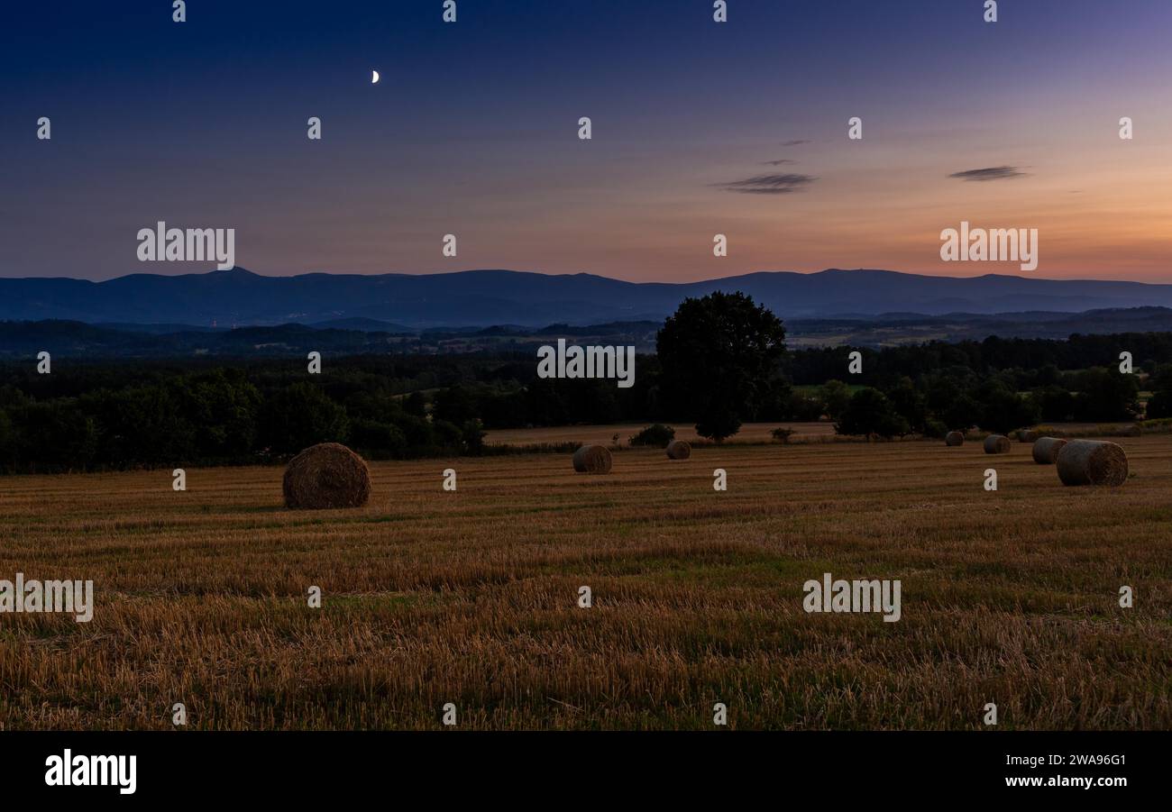Blick auf Stoppeln und Strohballen bei Nacht. Im Hintergrund das Karkonosze-Gebirge. Radomierz, Polen, Europa Stockfoto