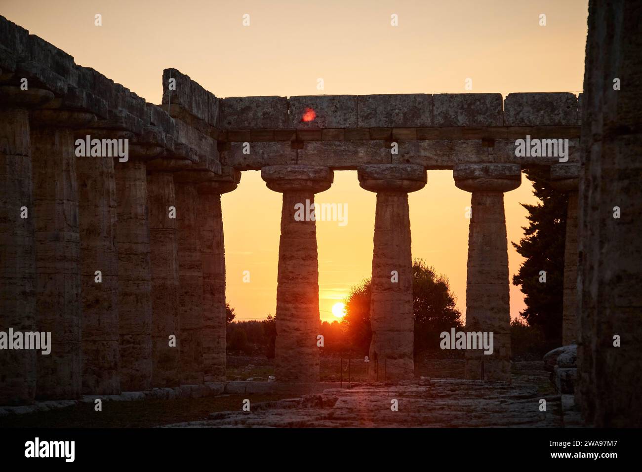 Die Sonne untergeht malerisch zwischen den alten Säulen einer Ruine, Sommerabendstimmung in Paestum, einer antiken Stadt 35 Kilometer südlich von Salerno. Gefunden Stockfoto