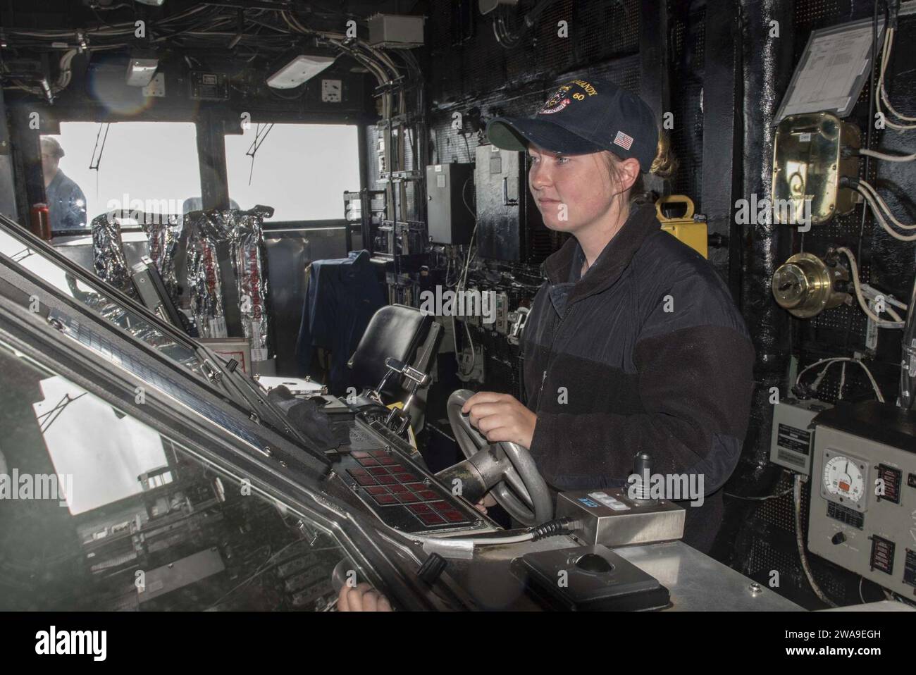US-Streitkräfte. 180707DZ642-0048 ATLANTISCHER OZEAN (7. Juli 2018) Seaman Haley Muething bemannt das Ruder auf der Brücke an Bord des Lenkraketenkreuzers USS Normandie (CG 60). Die Normandie ist derzeit Teil der Harry S. Truman Carrier Strike Group. Mit Harry S. Truman als Flaggschiff wurden Stab, Schiffe und Flugzeuge der Carrier Strike Group (CSG) 8, der Destroyer Squadron (DESRON) 28 und des Carrier Air Wing (CVW) 1 sowie der Sachsen-Klasse FGS Hessen (F 221) eingesetzt. (Foto der US Navy von Mass Communication Specialist 2nd Class Bobby Siens/veröffentlicht) Stockfoto