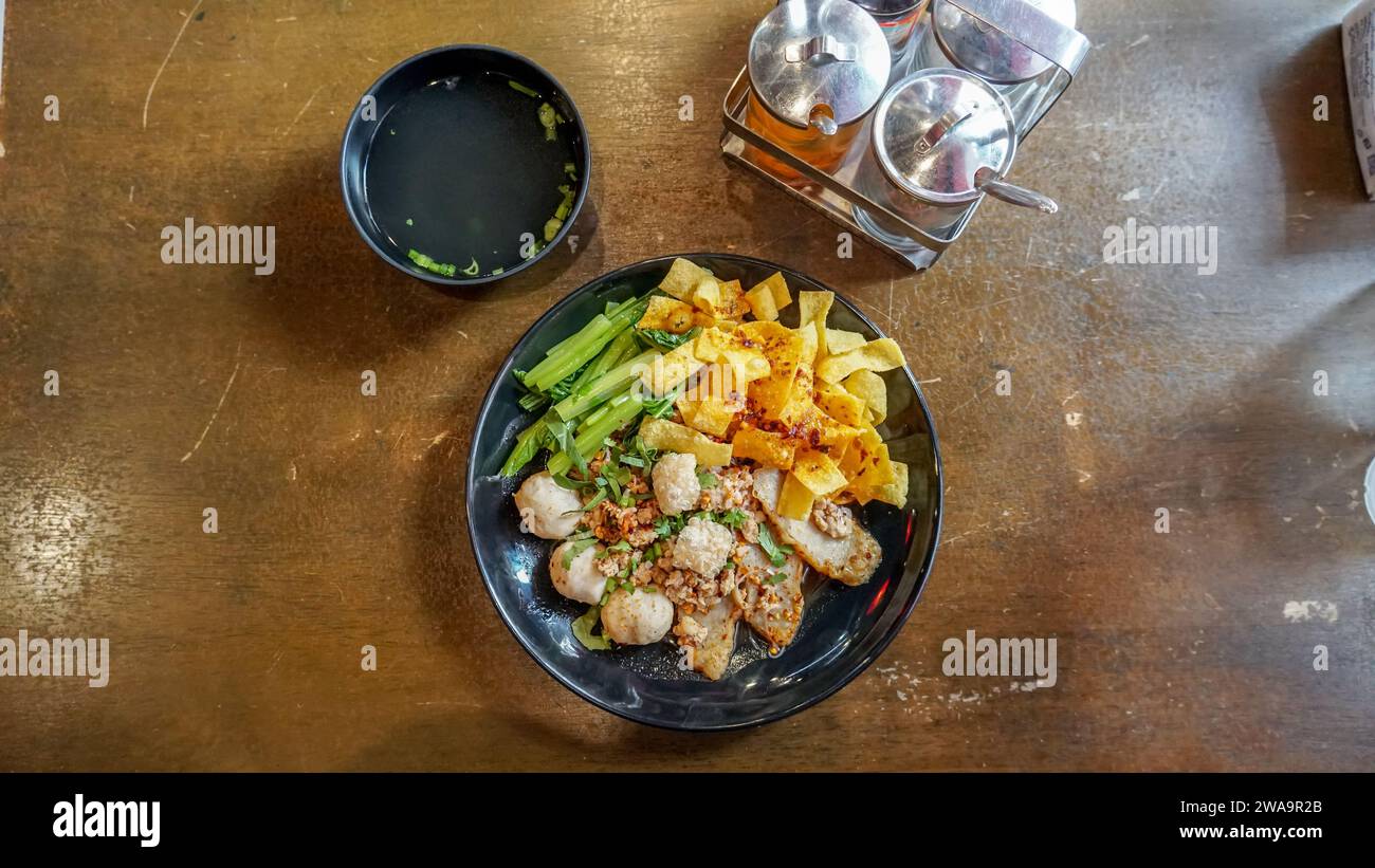 Getrocknete Eiernudeln mit Schweinefleisch Wonton oder Schweineknödel mit Suppe nach asiatischer Art. Thai scharfe getrocknete Reisnudeln mit Schweinefleisch, Fischbällchen, Garnelenbällchen und Stockfoto