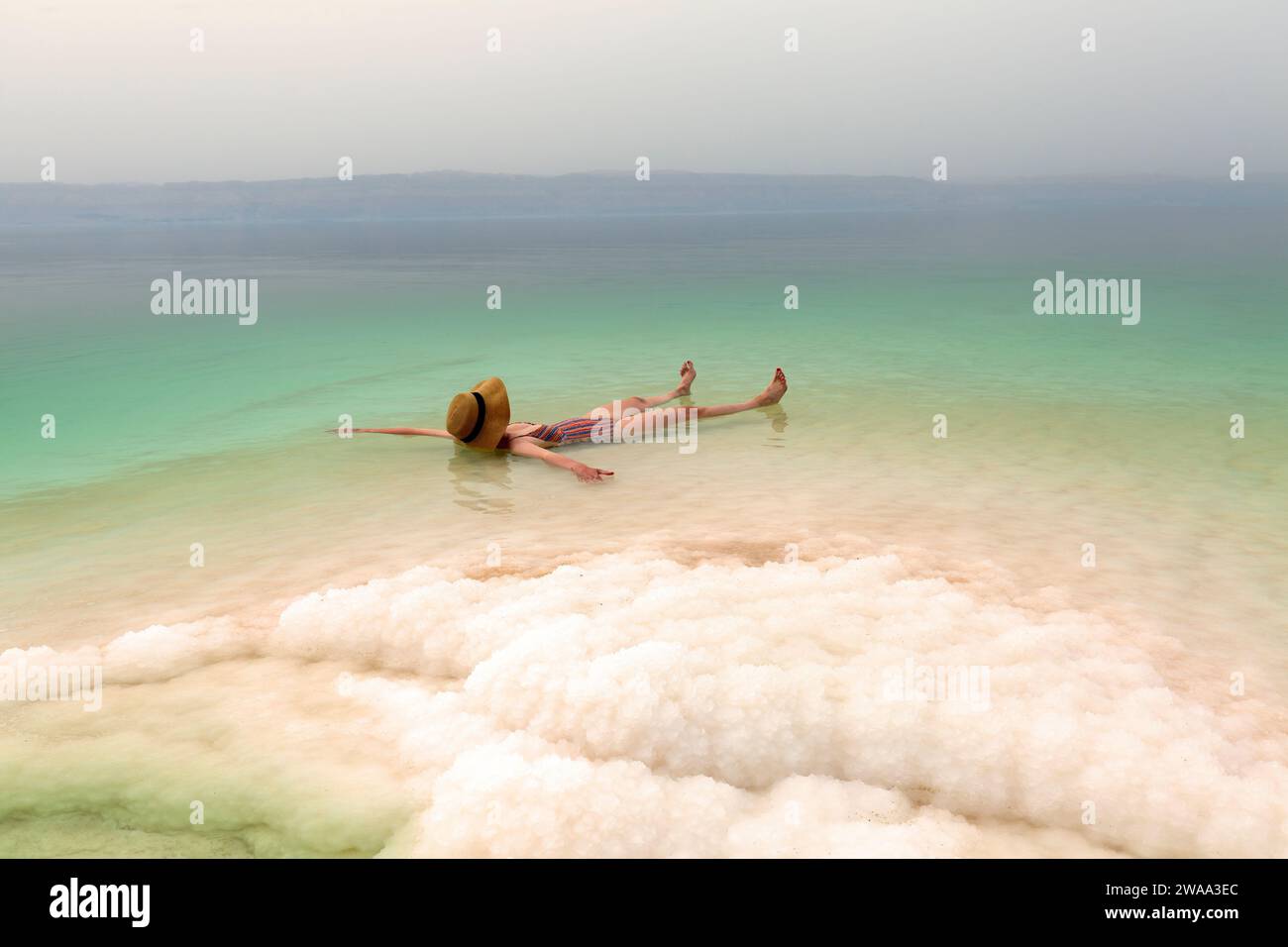 Frau mit Hut, die sich in salzigem Wasser des Toten Meeres entspannt Stockfoto