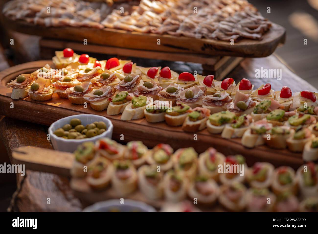 Kleine Sandwiches, Canape, serviert bei einer Veranstaltung auf einem Holzbrett. Verschiedene sichtbare, vegetarische und Fleischsorten sind verfügbar. Stockfoto