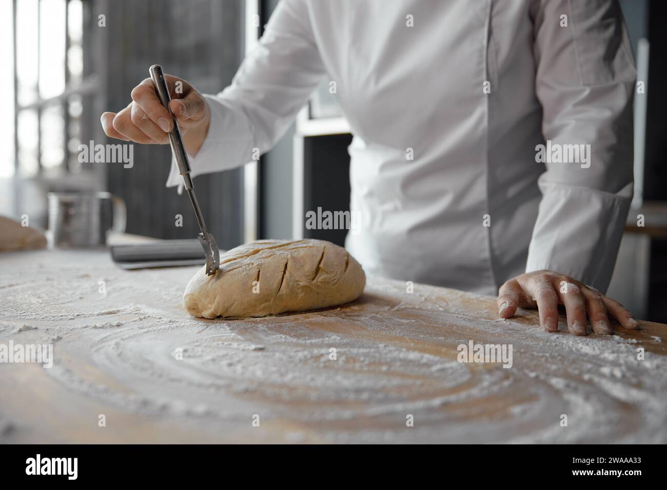 Nahaufnahme weibliche Köchinnen, die Teigschmuck machen, um Brotbrötchen zu dekorieren Stockfoto