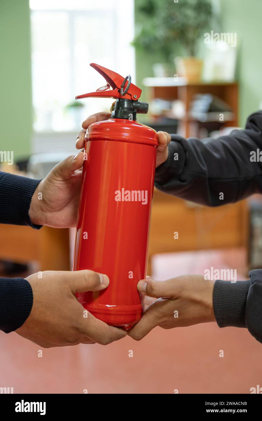 Mitarbeiter halten einen Feuerlöscher im Büro. Das Konzept des Brandschutzes Stockfoto