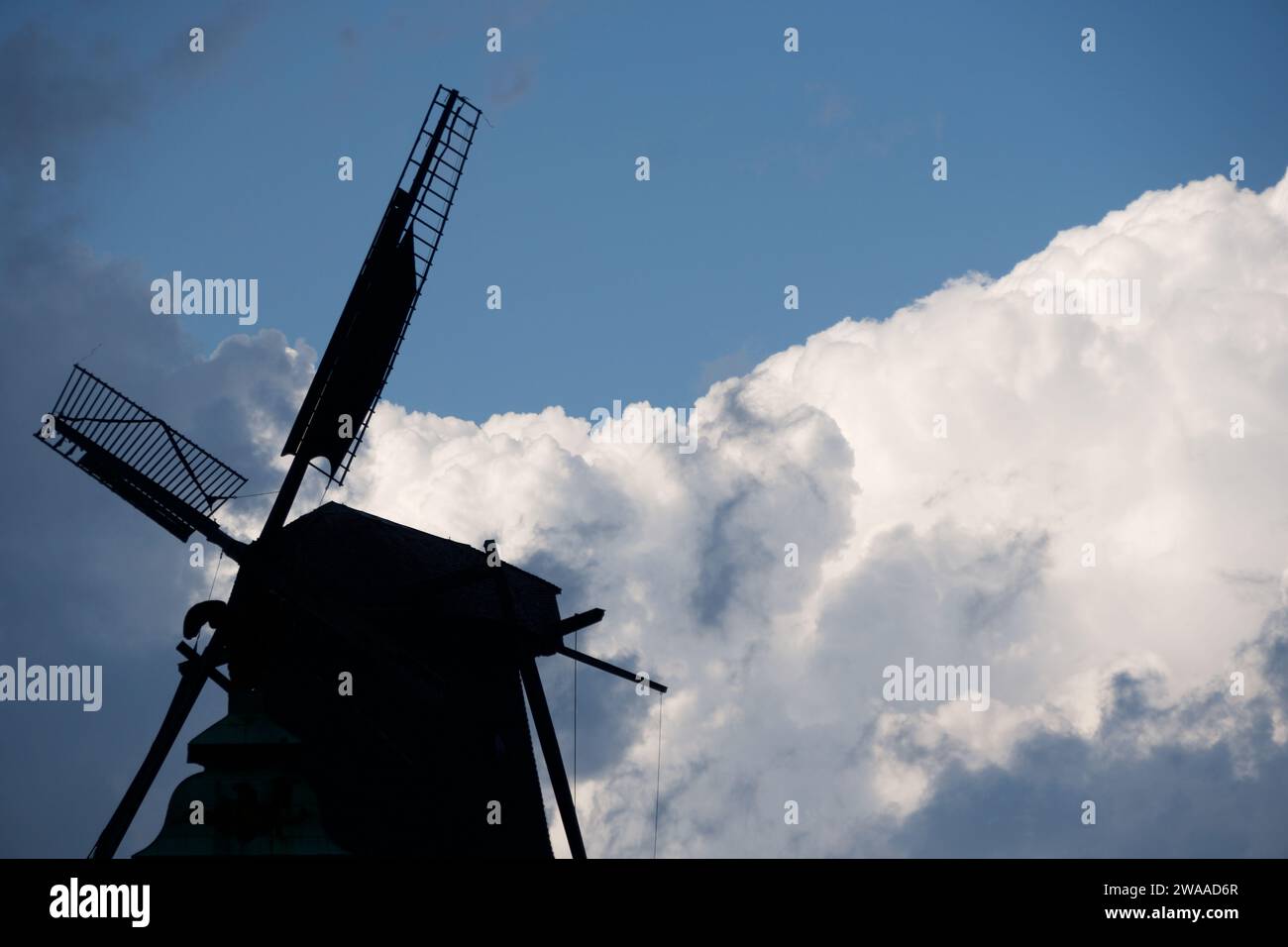 Die schroffe Silhouette einer traditionellen Windmühle hebt sich von der dramatischen Wolkenlandschaft ab und erinnert an die ländliche Geschichte in Potsdams sich entwickelndem A Stockfoto