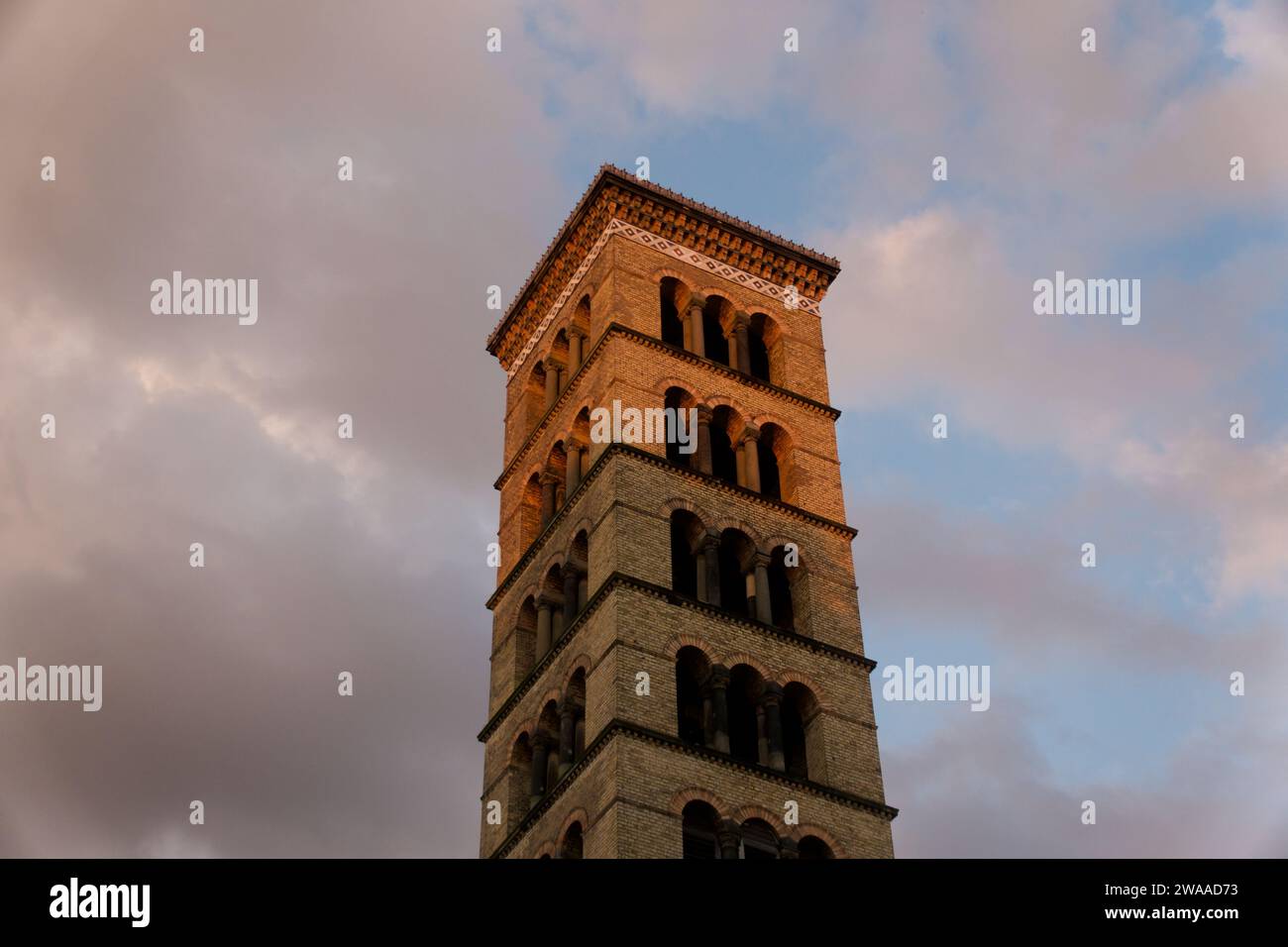 Während die Sonne untergeht, erleuchtet sein warmes Leuchten einen kunstvollen historischen Turm in Potsdam, der die komplizierten Details und das romantische Ambiente der Stadt unterstreicht Stockfoto