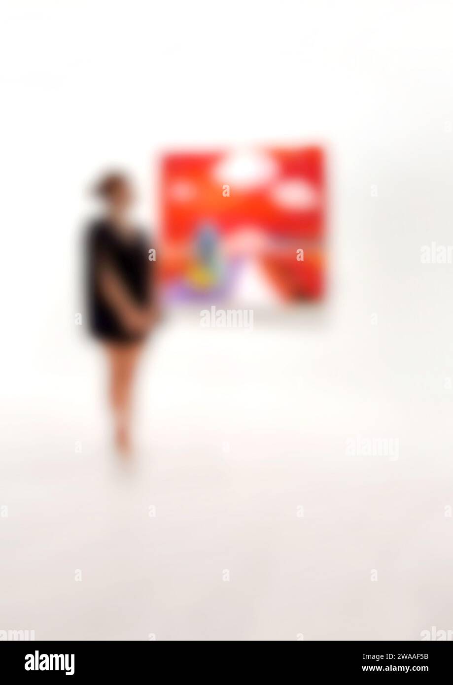 Kunstgalerie mit verschwommenem Hintergrund und Frau, die Gemälde an der weißen Wand ansieht. Stockfoto