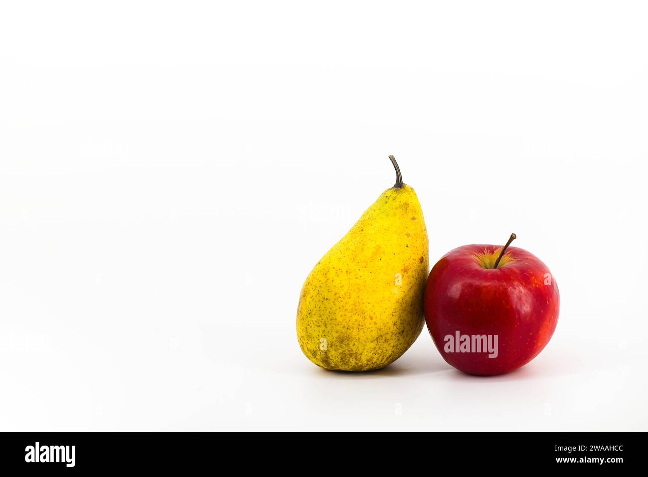 Ein lebendiges Bild mit einer gelben Birne und einem roten Apfel auf einem makellos weißen Hintergrund. Die kontrastierenden Farben schaffen eine optisch ansprechende Komposition Stockfoto