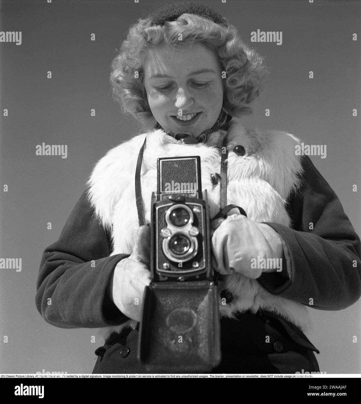 Winter in den 1940er Jahren Eine junge Frau fotografiert an einem Wintertag. Die Kamera ist eine Rolleiflex der deutschen Firma Rollei für 60-mm-Filme. 1944. Foto Kristoffersson Ref. F104-4 Stockfoto