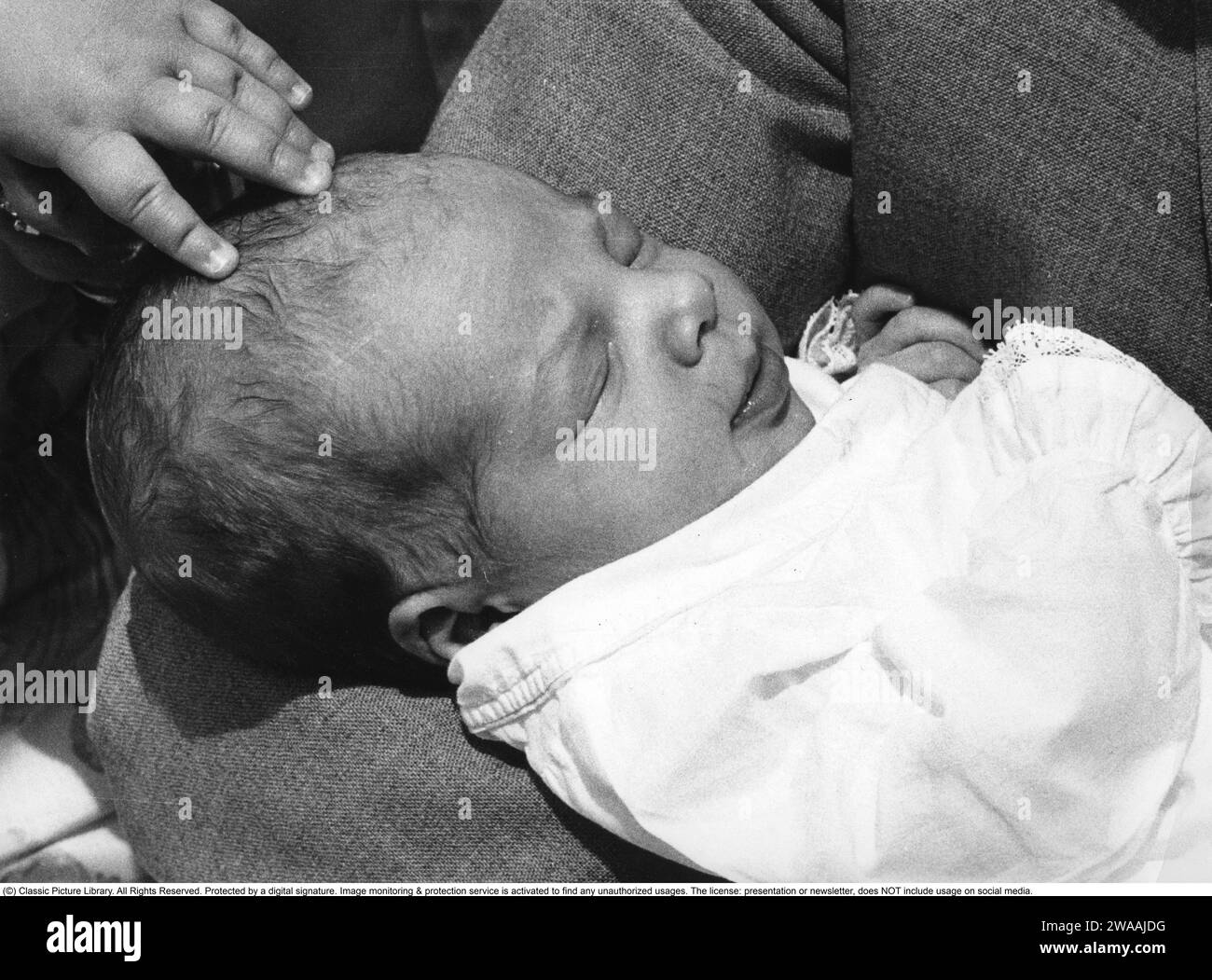 Prinz Joachim von Dänemark. Geboren 1969 und jüngster Sohn von Königin Margarethe und Prinz Henrik. Hier aus der Taufe im Aarhus-Dom am 15. Juli 1969, wo Margrethe ihn vor dem Taufbecken hält und der Priester ihn als Joachim Holger Waldemar Christian tauft. Die schwedische Prinzessin Christina und die dänische Prinzessin Benedikte nehmen als Paten Teil. Stockfoto