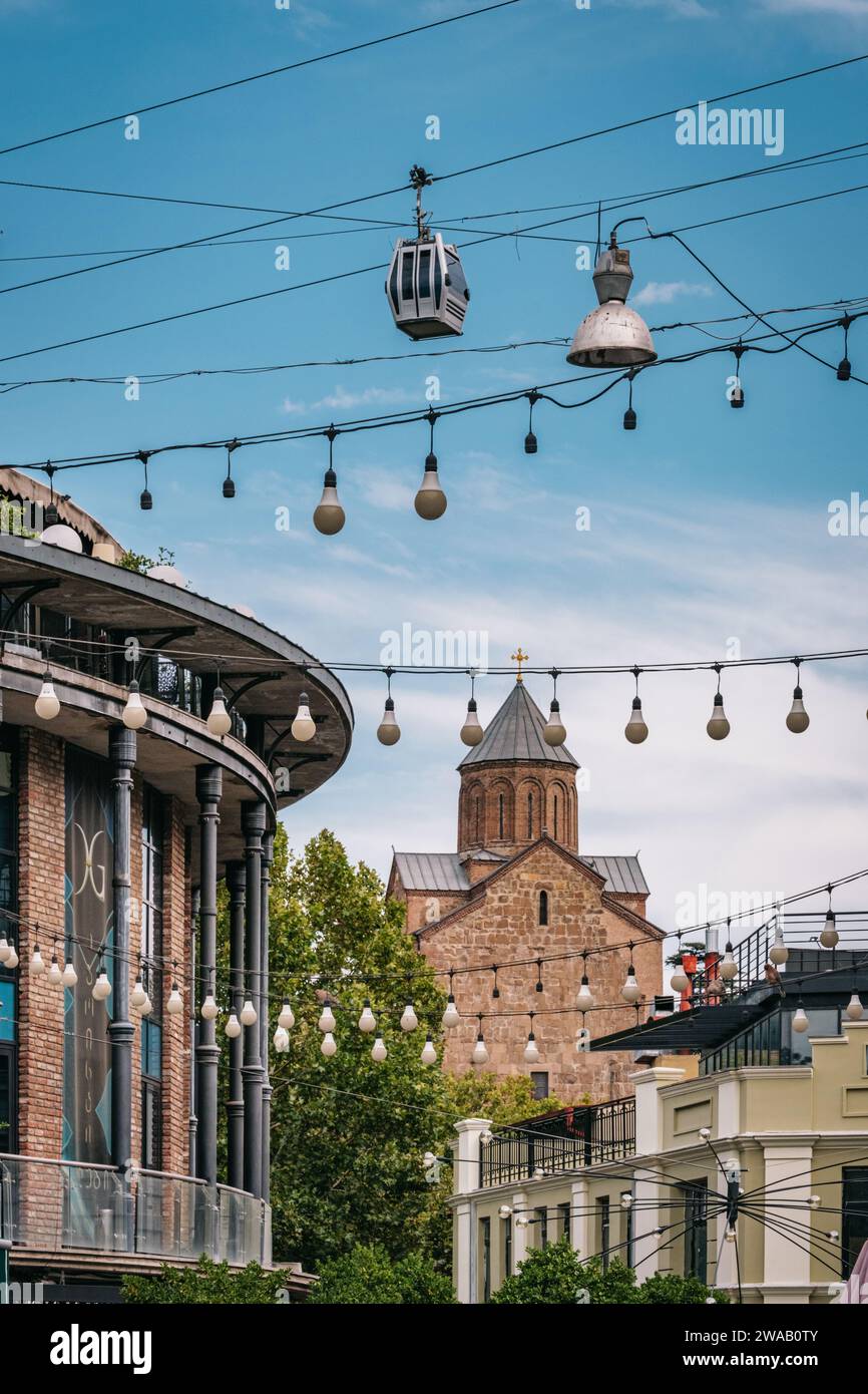 Blick auf die Kirche von Metekhi und die Seilbahn von Tiflis zwischen den hellen Girlanden der Baumwollreihen (Shardeni-Straße) in Kala, der Altstadt von Tiflis in Georgien Stockfoto