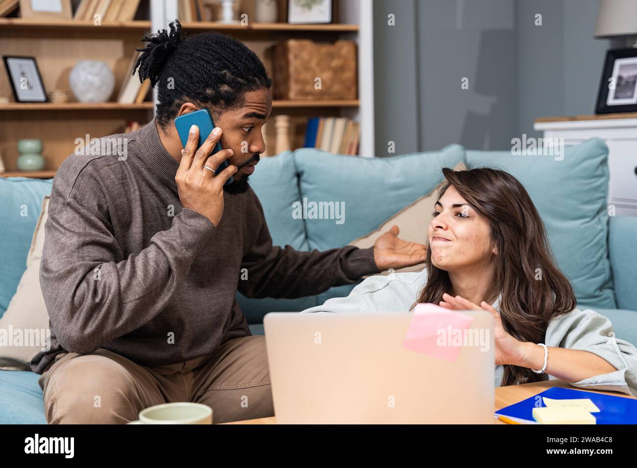Junge freischaffende gemischte Rassen-Paar Kleinunternehmer, die im Heimbüro an einem Laptop arbeiten, Probleme mit der Internetverbindung oder Firmen-Web-pag Stockfoto