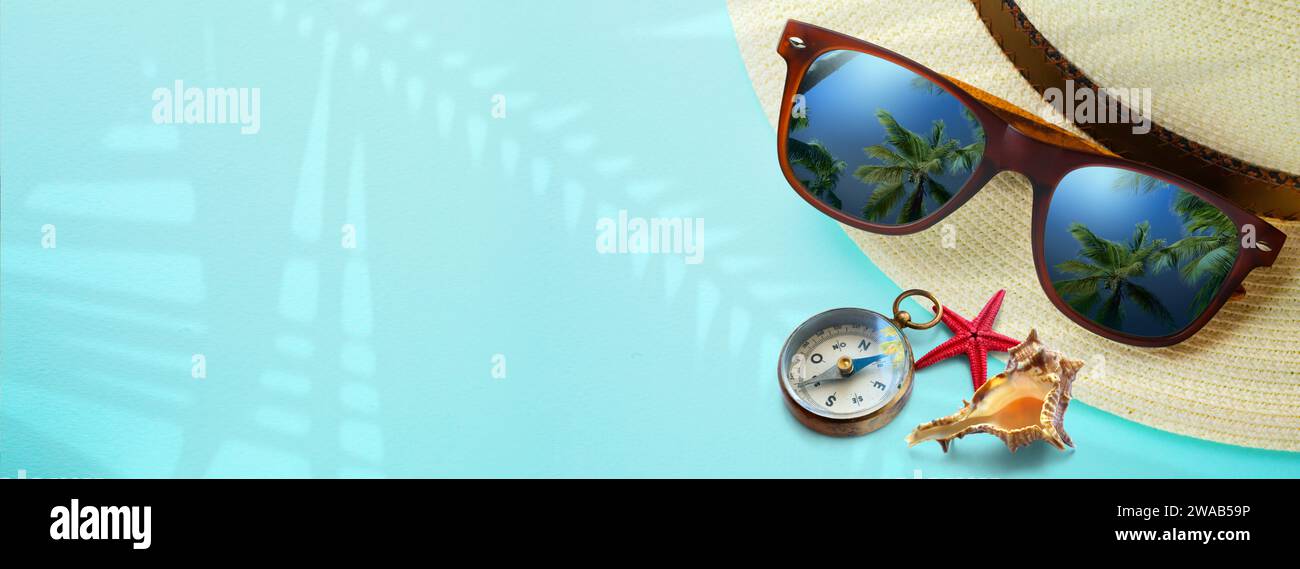 Konzept Urlaub und Sommer Reise Banner. Frohe Ferien am tropischen Strand. Panamahut, Kompass, Sonnenbrille mit einer Reflexion des Sandtrovic Stockfoto