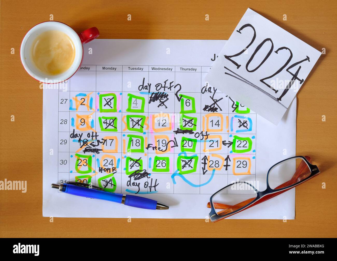 Kalender mit Geschäftsterminen für das neue Jahr 2024, Stift, Kaffeetasse und Brille, monatlicher Zeitplan mit freien Tagen für eine bessere Balance zwischen Leben und Arbeit.B Stockfoto
