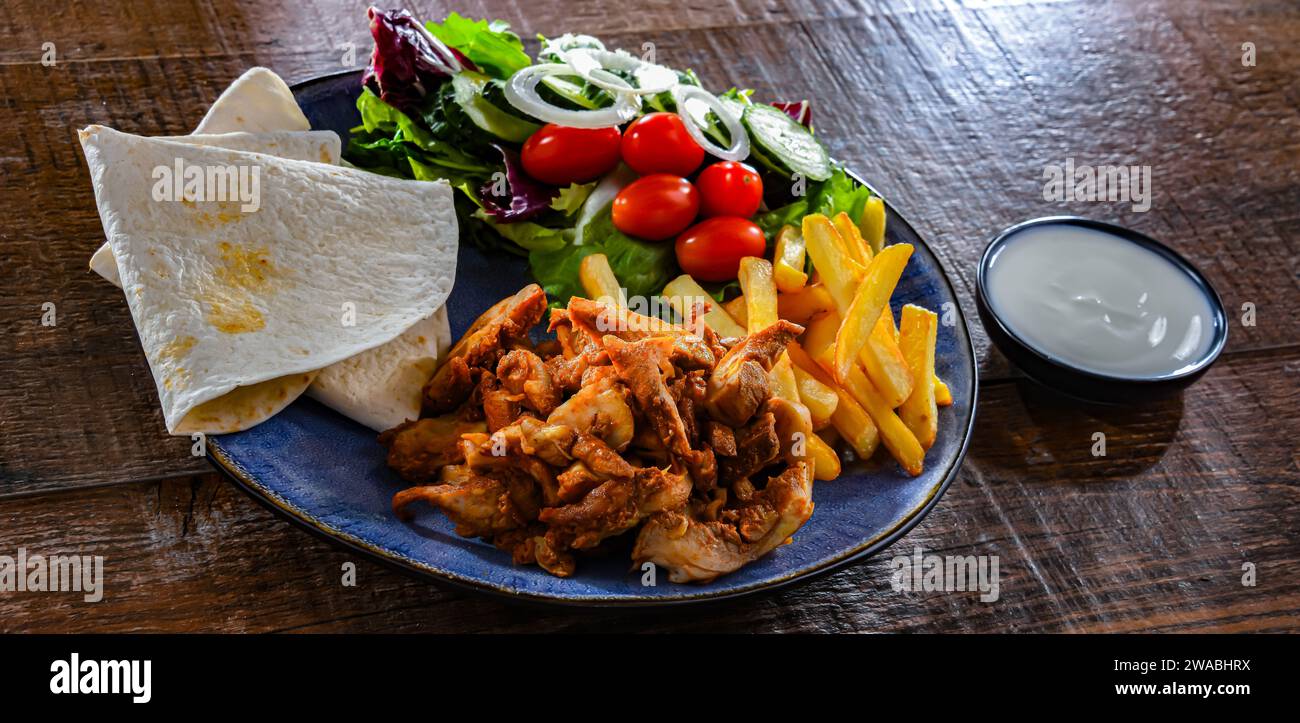 Kebab serviert mit Pommes frites, Pitta-Brot, Gemüse und Tzatziki Stockfoto