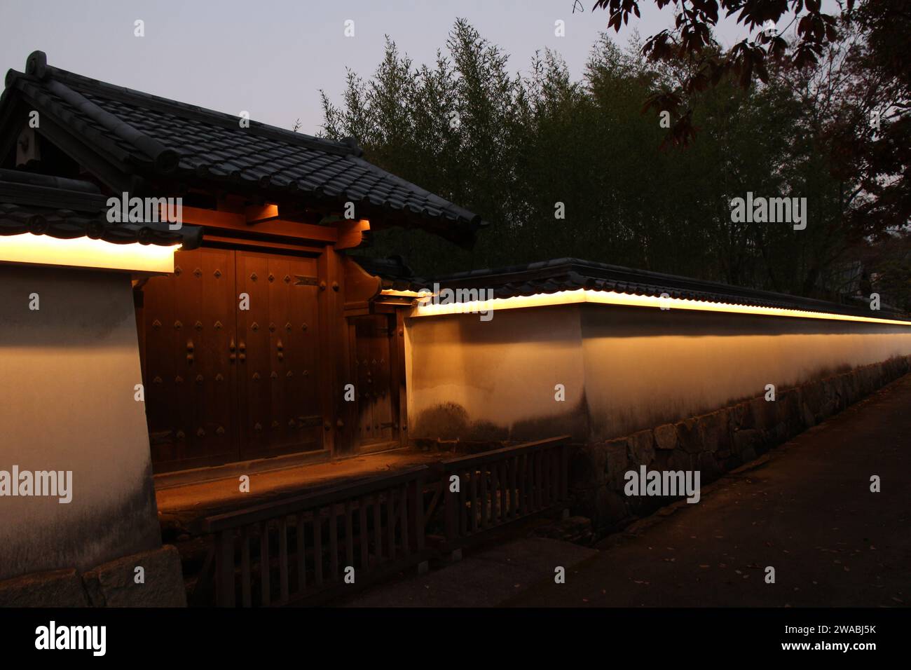 Holztor und Beleuchtung des Koko-en Garden in der Abenddämmerung, Himeji, Japan Stockfoto