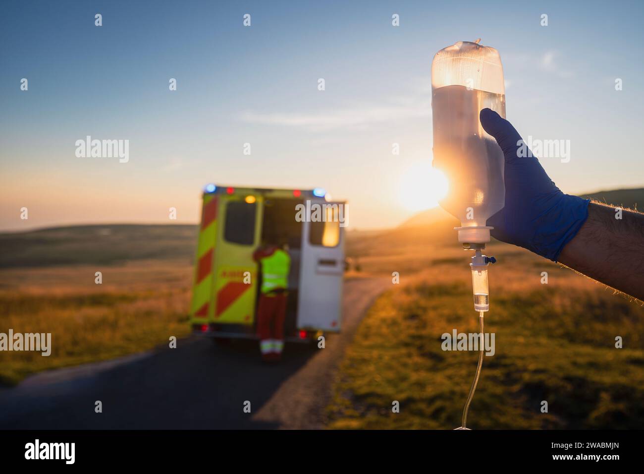 Close-up-Hand eines Sanitäters, der IV-Tropf gegen Ambulanzwagen des Notarztdienstes hält. Themen Rettung, Dringlichkeit und Gesundheitsfürsorge. Stockfoto