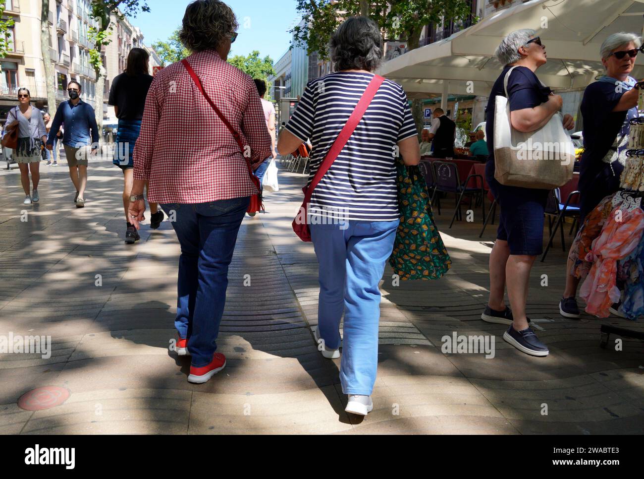 Barcelona, Spanien - 26. Mai 2022: Zwei ältere Frauen mit grauem Haar und bequemer Kleidung, beide mit roten Taschen, spazieren entlang der Ramblas von Ba Stockfoto