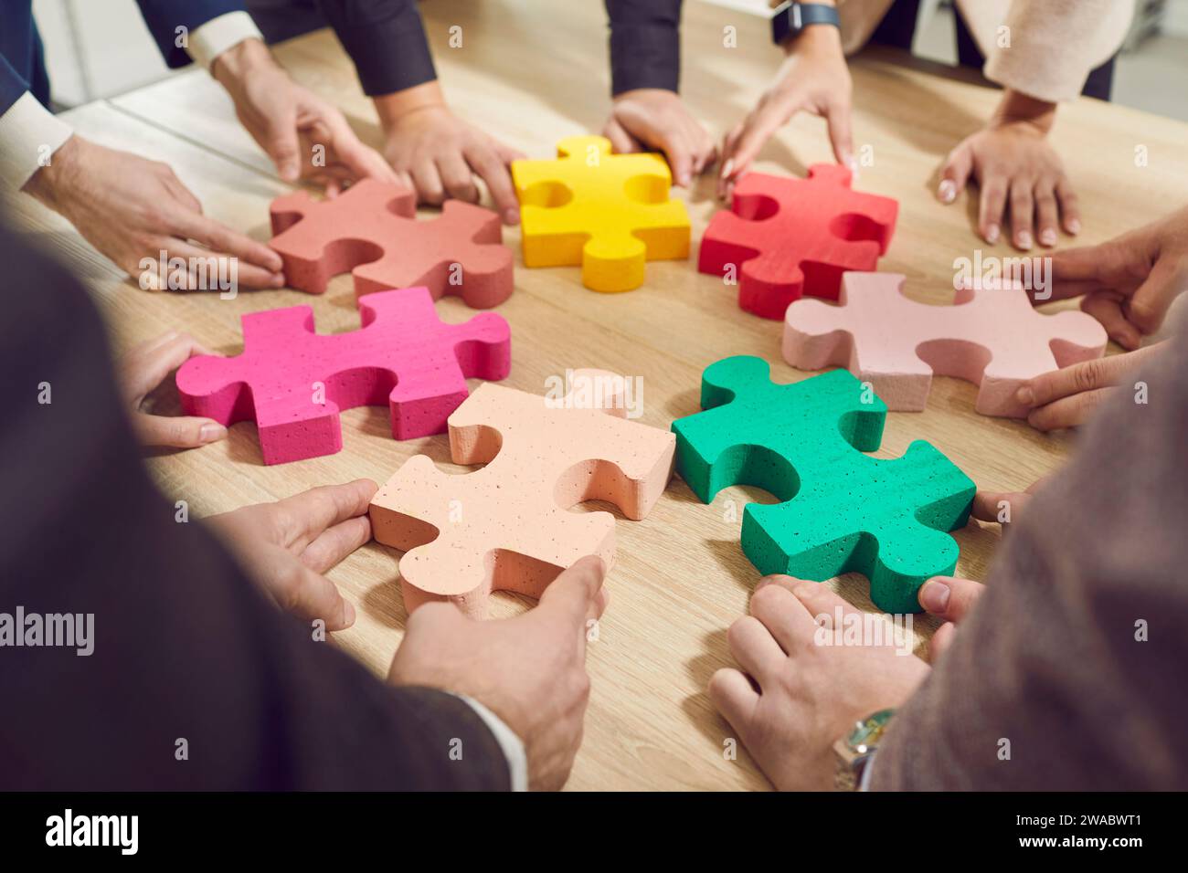 Geschäftsleute stellen bunte Puzzles auf den Desktop und präsentieren das Konzept der Zusammenarbeit, Teamarbeit, Unterstützung und Unterstützung im Büro. Stockfoto