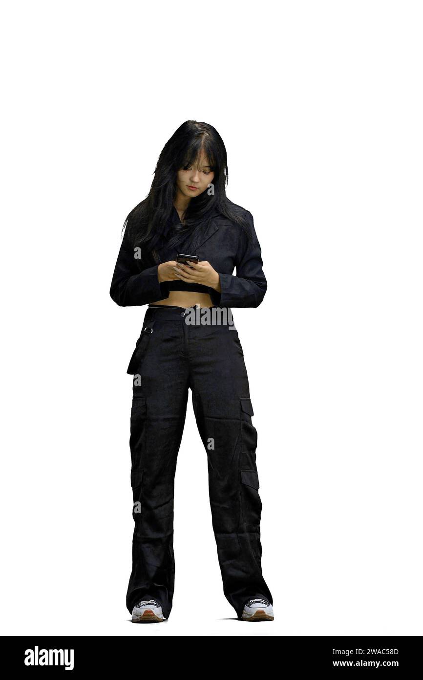 Eine Frau in schwarzer Kleidung, auf weißem Hintergrund, in voller Länge, mit einem Telefon Stockfoto