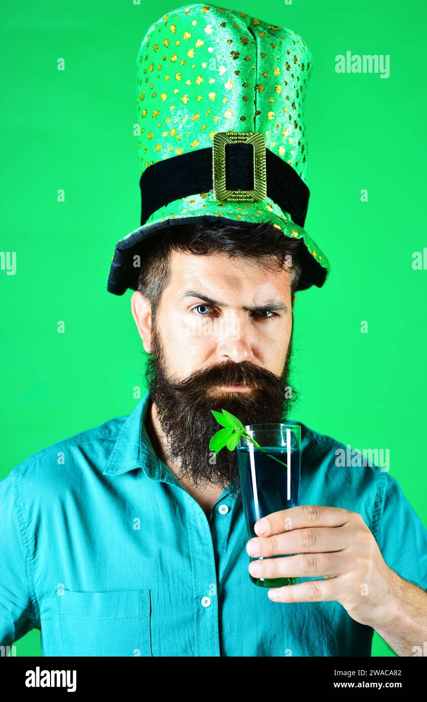 Feierlichkeiten zum Heiligen Patricks-Tag. Bärtiger Mann mit Kobold-Hut und einem Glas grünes Bier. Patrick Day Pub Party. Nahaufnahme Porträt ernster Mann in Grün Stockfoto