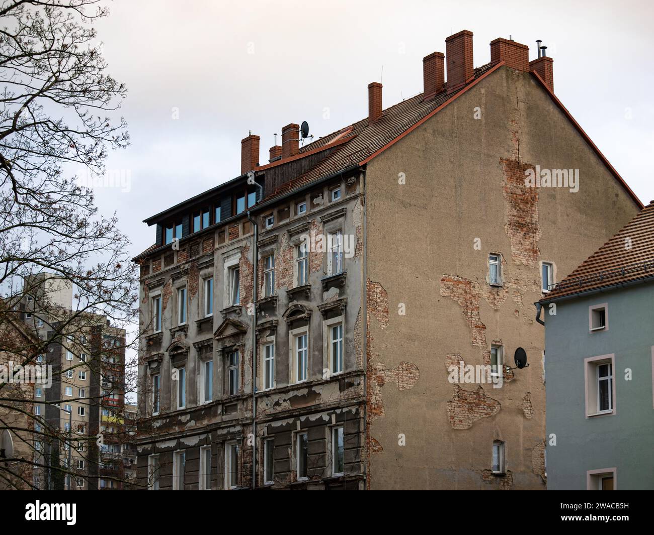 Heruntergekommenes Appartementgebäude in einem Wohnviertel. Die Fassade ist gebrochen und beschädigt, Risse im Putz und die rohe Ziegelwand ist sichtbar. Stockfoto